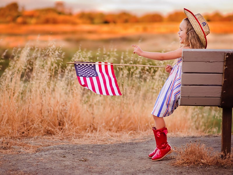 Labor Day celebration girl in cowboy hat holding flag